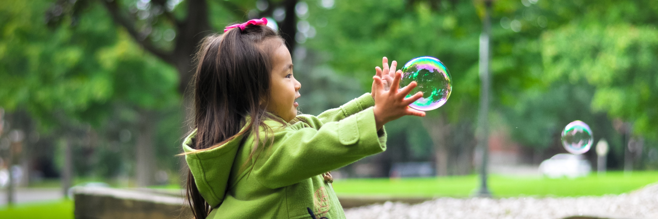 8 Lessons I've Learned From Teaching Autistic Children Little Asian-American girl playing with bubbles.