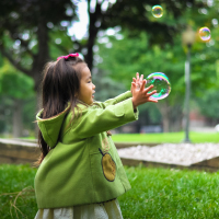 Little Asian-American girl playing with bubbles.