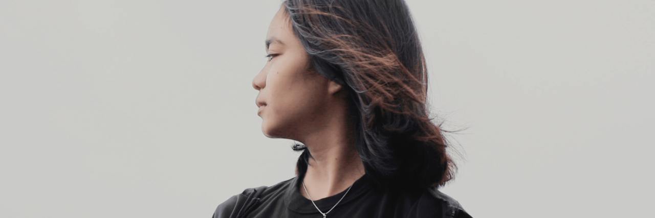 How to Cope When You See Eating Disorder Triggers photo of young woman against gray sky, looking into distance