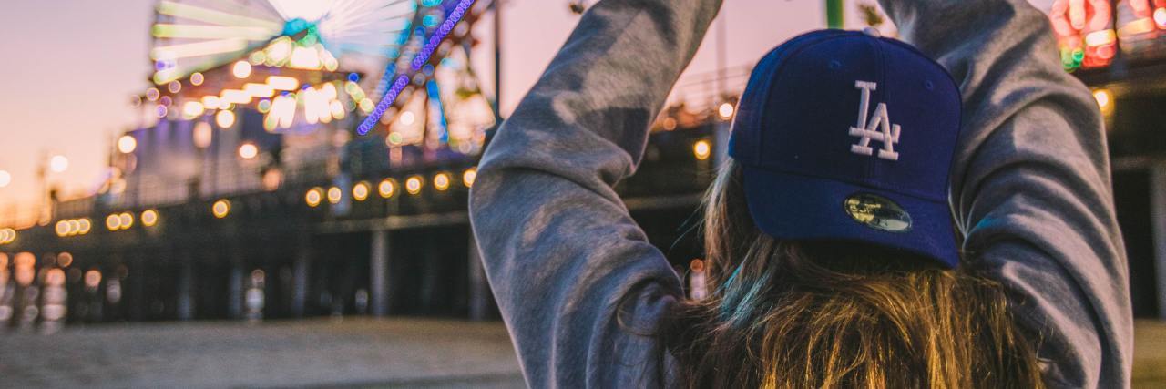 photo of a woman in front of a roller coaster at sunset