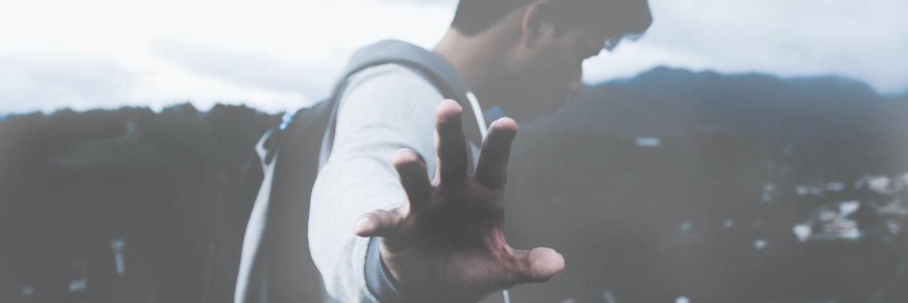 Life Events That Could Have Contributed to My Schizophrenia Diagnosis A man in fog holding up his hand