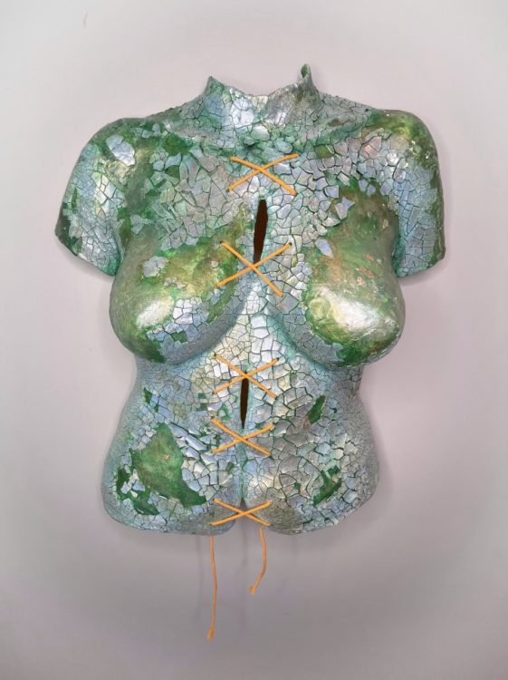 Body cast sculpture "Broken Body": torso in sea green color, covered in shining, cracked silvery pieces. String tied down the middle in a series making an "X" shape (shown from center angle)