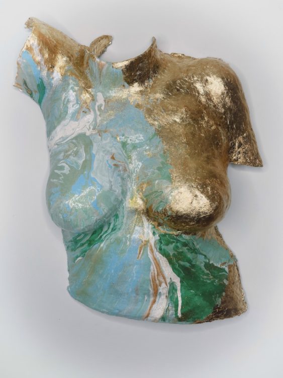 Body cast sculpture "Enduring Spirit" of torso with one side painted in gold and the other in a mix of swirling green, white and blue (shown from center angle)