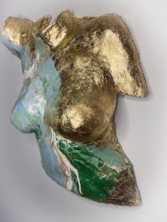 Body cast sculpture "Enduring Spirit" of torso with one side painted in gold and the other in a mix of swirling green, white and blue (shown from right angle)