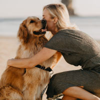 a woman kissing her dog on the beach