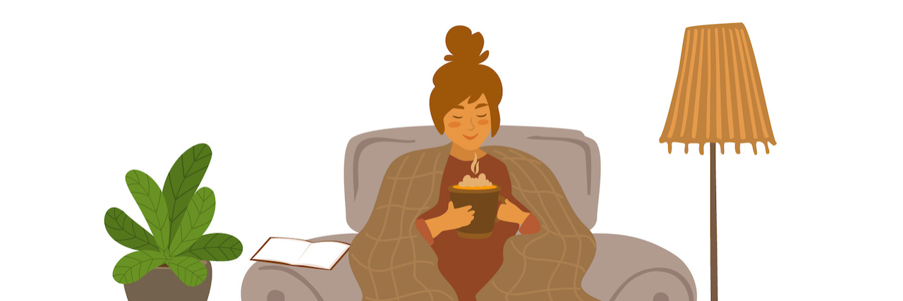 Woman sitting on a couch at home with large cup of a steaming drink