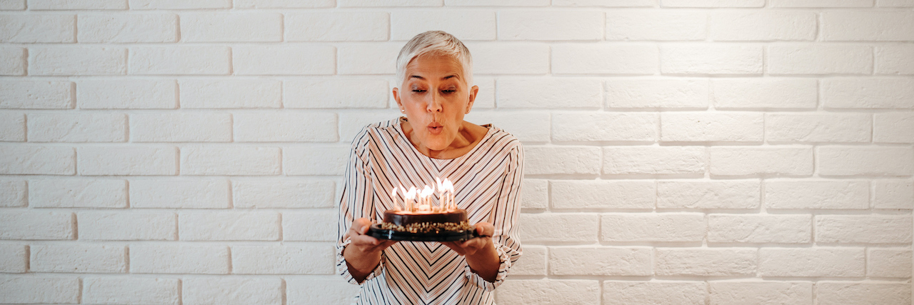 My Mother's Cancer Remission Was Not the Celebration I Expected Woman with short white hair blowing birthday candles