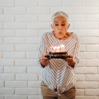 Woman with short white hair blowing birthday candles