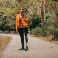 Woman with prosthetic leg standing in the park.