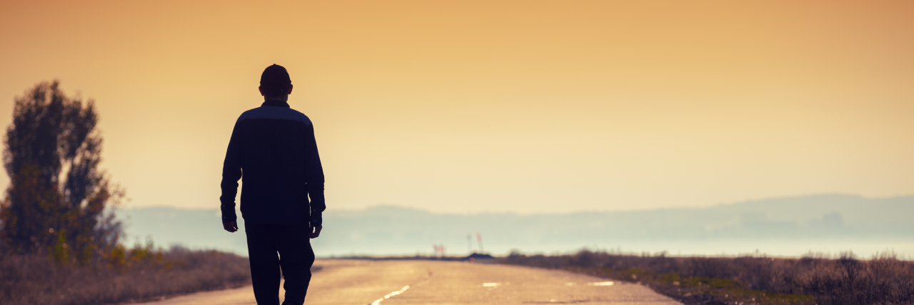 Living Life With Cerebral Palsy on My Own Terms Man walking down a road at sunset.