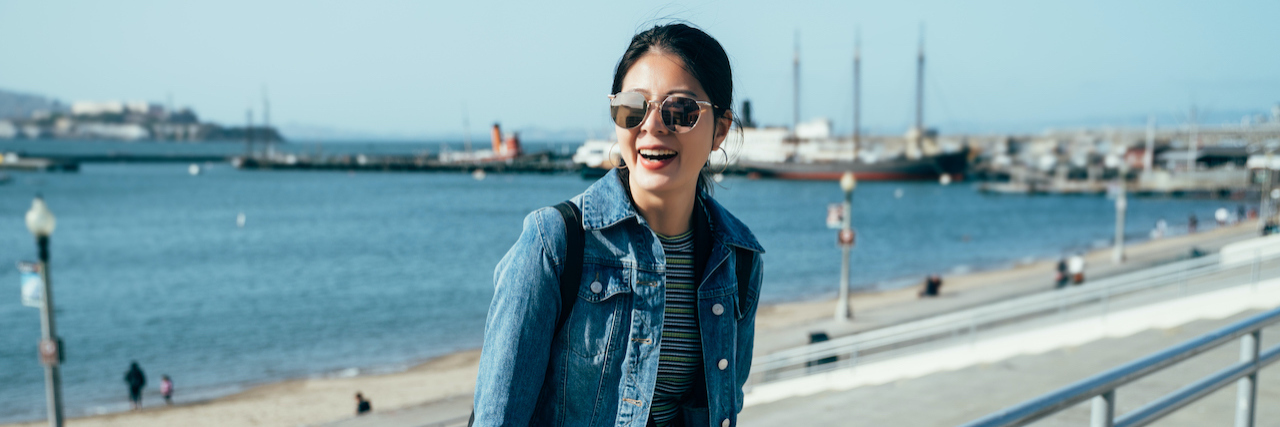 Asian woman smiling on pier by water