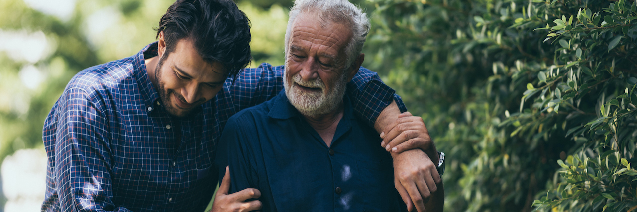 When Surviving Is Just the Beginning With Cancer Father and adult son walk outside together, embracing