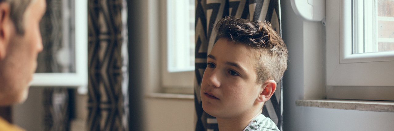 The Rising Problem of Suicide in Young Adult Men Father near outside frame of photo looking at serious son in the center