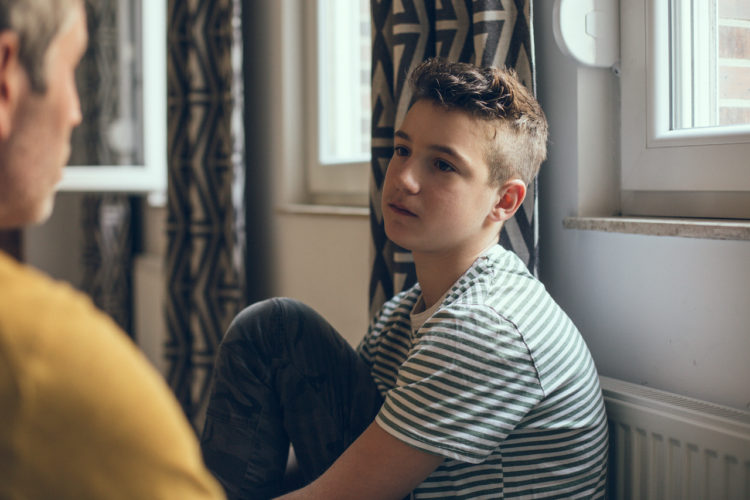 Father near outside frame of photo looking at serious son in the center