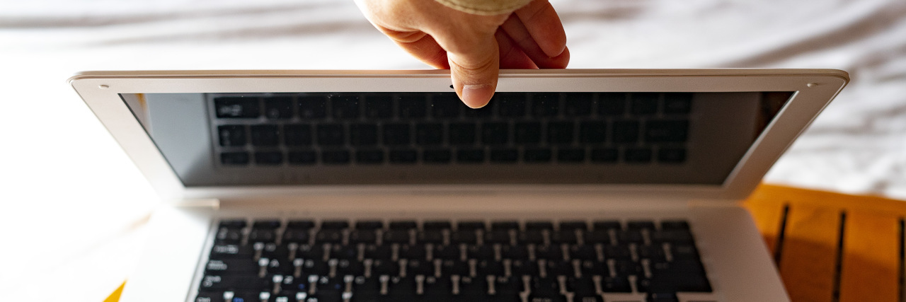 Hand closing a laptop.