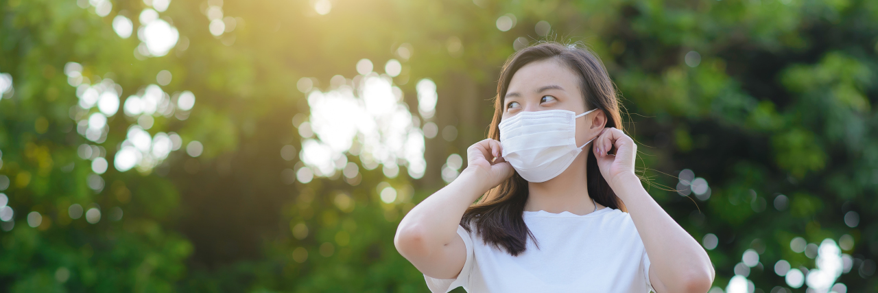 My Struggle Through the Pandemic as an Autistic Woman Woman putting on a face mask.