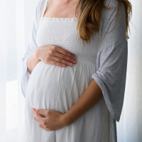 Pregnant woman standing by window.