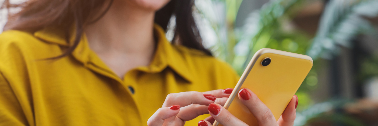 KHN: In a Murky Sea of Mental Health Apps, Consumers Left Adrift A woman in a yellow shirt using a smartphone