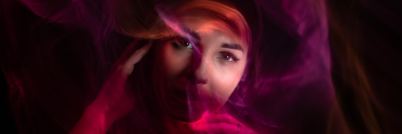The Emotional Extremes I Feel With Borderline Personality Disorder Photo of a woman's face with abstract purple/pink lines swirling her face