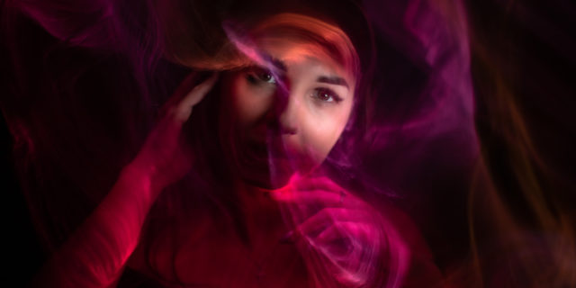 Photo of a woman's face with abstract purple/pink lines swirling her face