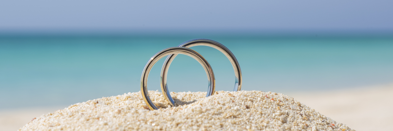 How the SSI Marriage Penalty Affects People With Disabilities Pair of wedding rings in sand on tropical beach