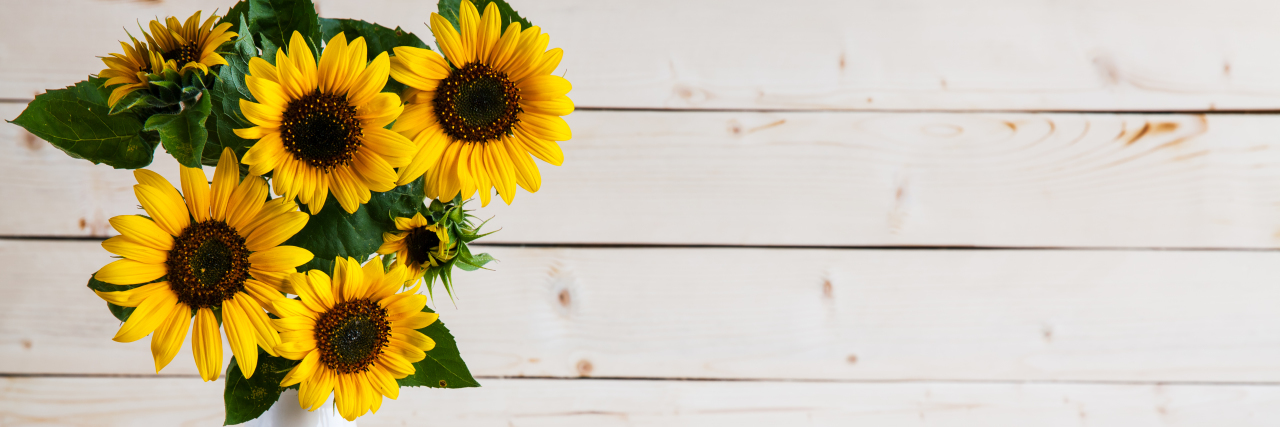 Sunflowers in a vase on rustic, gray background.