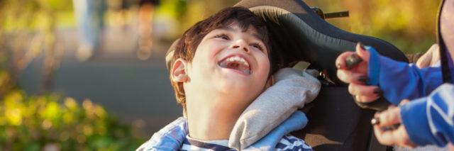 Smiling boy in wheelchair enjoying time at park.