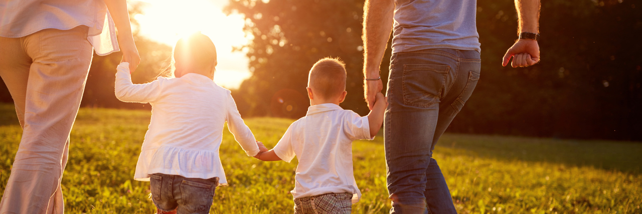 The Choices I Make Because of My Child's Hurler Syndrome Parents holding hands with their children at sunset.