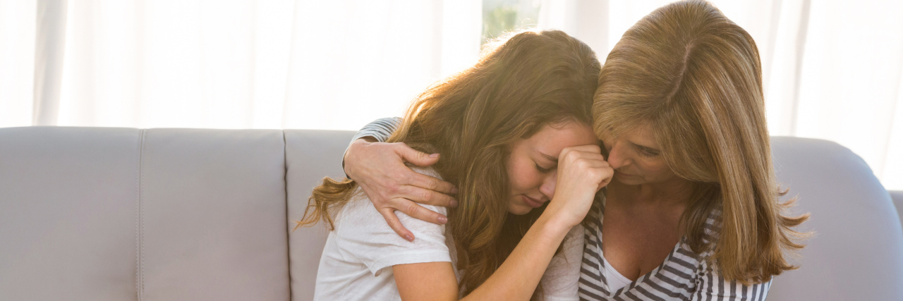 A Mother and Daughter's Journey With Depression A mother sitting on the couch with her teenage daughter, comforting her