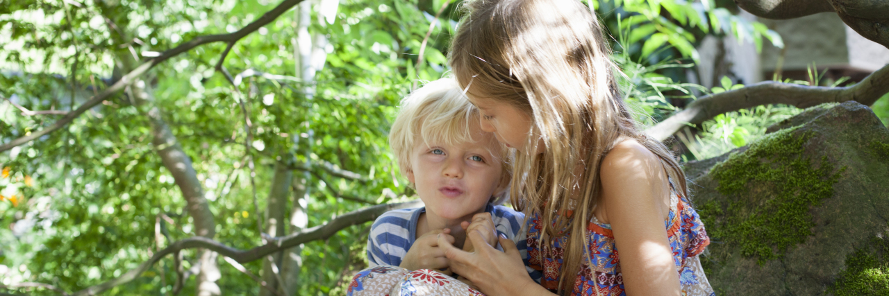 How Having a Sibling With a Disability Can Change Kids for the Better Siblings hugging under a tree.