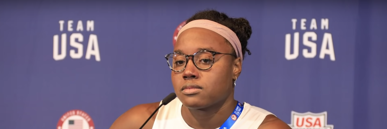 Athlete Showcases How Burnout Can Lead to Symptoms of Depression Simone Manuel sits at a press conference where she's explaining what overtraining syndrome is like