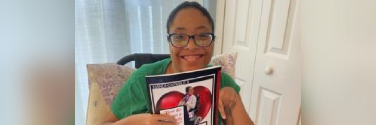 Author, a Black woman in glasses smiling holding up a magazine