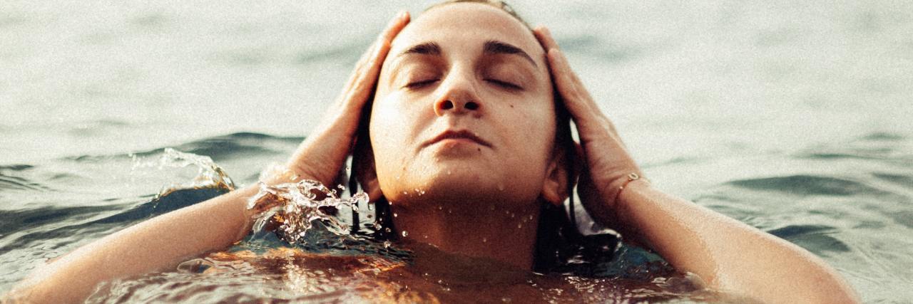 Why My Depression Might Be a Combination of Bipolar and Hypothyroidism photo of a woman in the ocean with her head raised and hands at the sides of her head