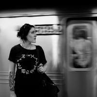 black and white photo of a woman in front of a passing train