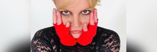 Britney Spears wearing a black lace shirt and red fingerless gloves.