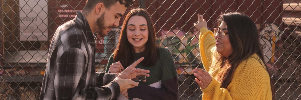 photo of three young people talking near a fence and smiling