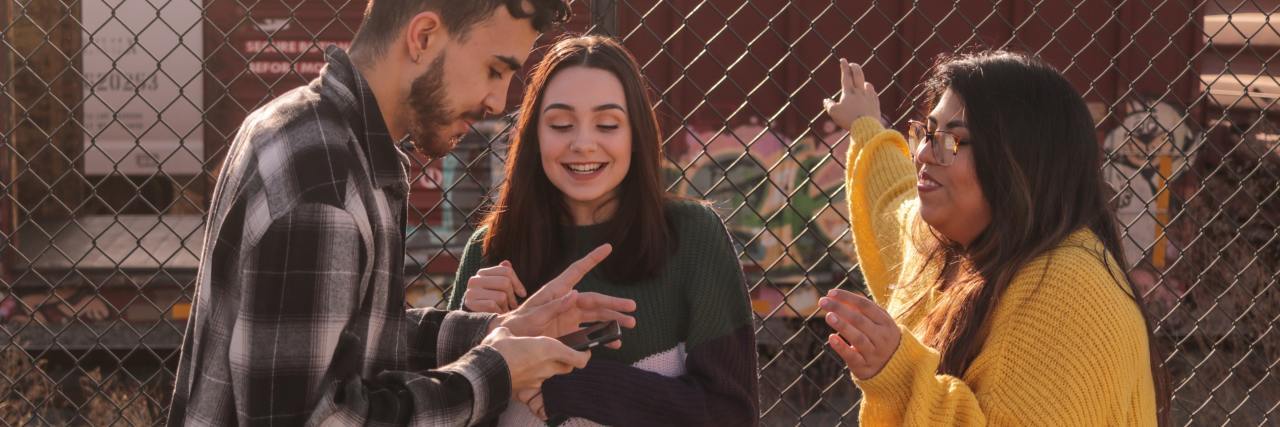 How to Support Youth Mental Health photo of three young people talking near a fence and smiling
