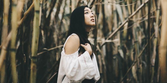 The Asian and Pacific Islander Community Needs to Change Its Mental Health Narrative photo of a woman standing among bare trees, looking upset