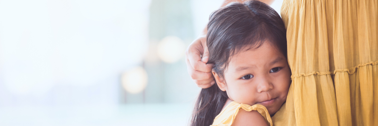 Young child hanging onto mother's leg