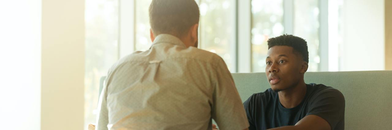 When Is It OK to Stop Seeing Your Therapist? photo of two men talking over a table beside a window