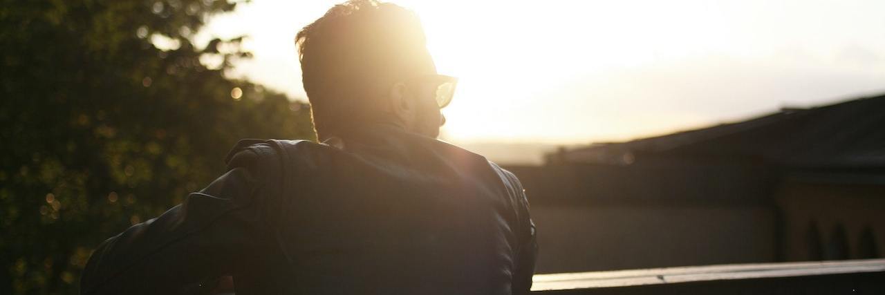 Surviving and Thriving With HIV Man looking out over beautiful natural area at sunset