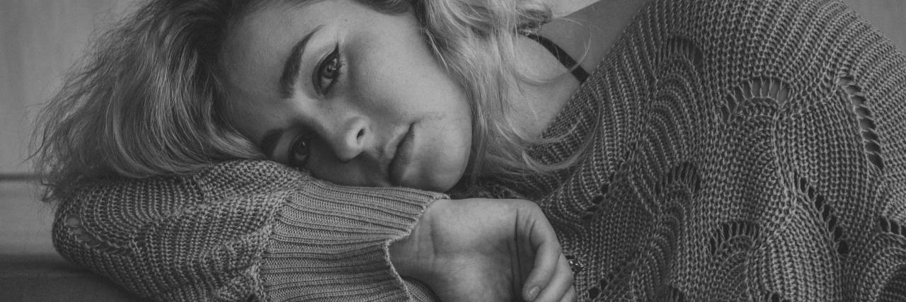 Signs You Might Be Experiencing a Major Depressive Episode black and white photo of a woman resting head on her arm and looking into camera with somber expression