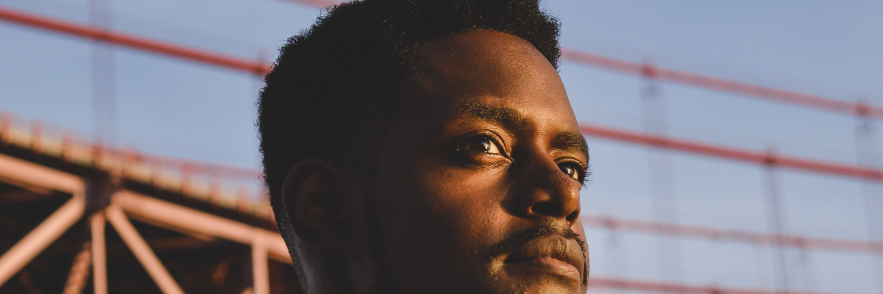 Looking Back on Race and Schizophrenia Black man standing outside in front of bridge