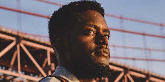 Looking Back on Race and Schizophrenia Black man standing outside in front of bridge
