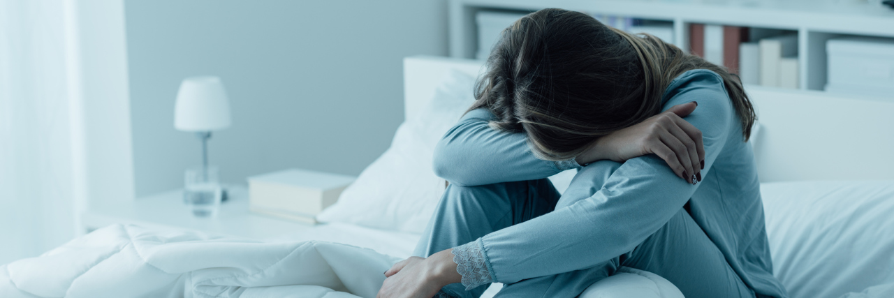 How Inflammatory Bowel Disease Can Impact Sleep A woman with brown hair leaning over in bed