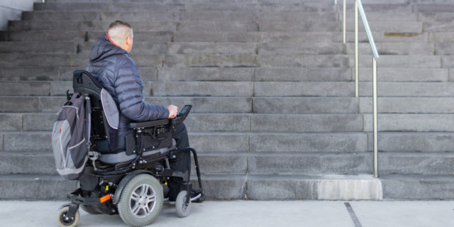 Man in power wheelchair looking at a flight of stairs.