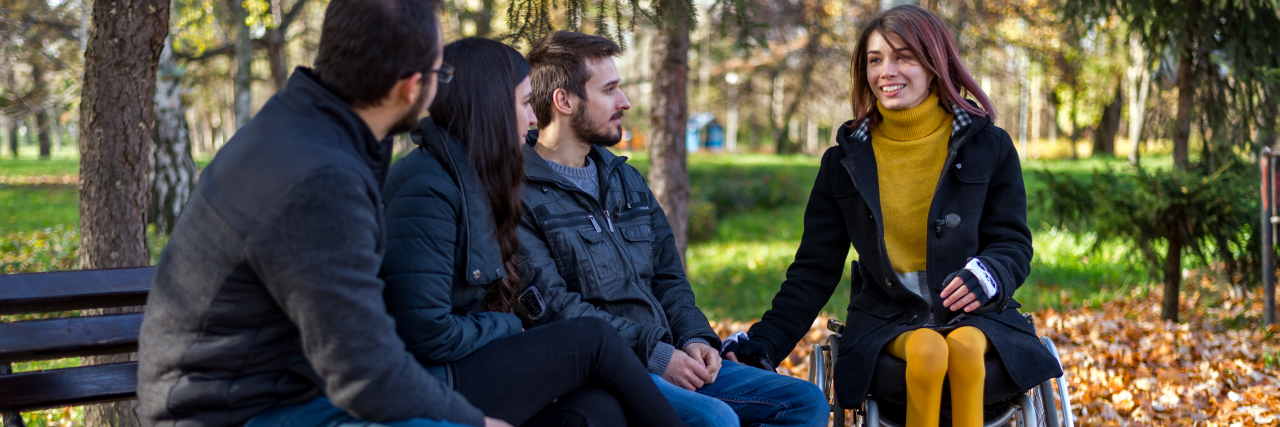 Please Don't Say This to Your Disabled Loved One's Friends Disabled young woman in a wheelchair enjoying a autumn sunny day with friends in the park.