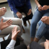photo of people in a circle meeting leaning forward in chairs