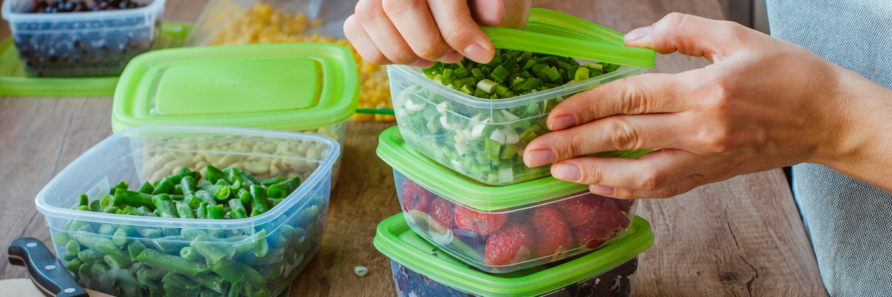 Close up of person's hands preparing plastic food boxes