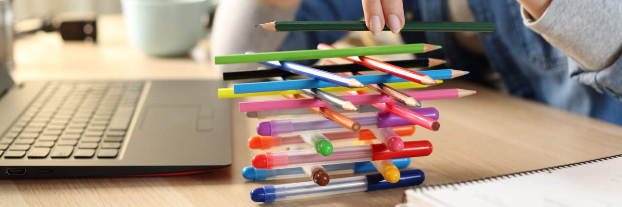 How I've Struggled to Get ADHD Treatment as a Woman Woman with ADHD fidgeting by stacking pens.
